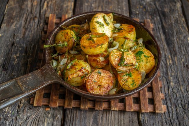 Молодая картошка, жаренная на сковороде с чесночными стрелками, готова Молодая картошка, жаренная на сковороде с чесночными стрелками, готова